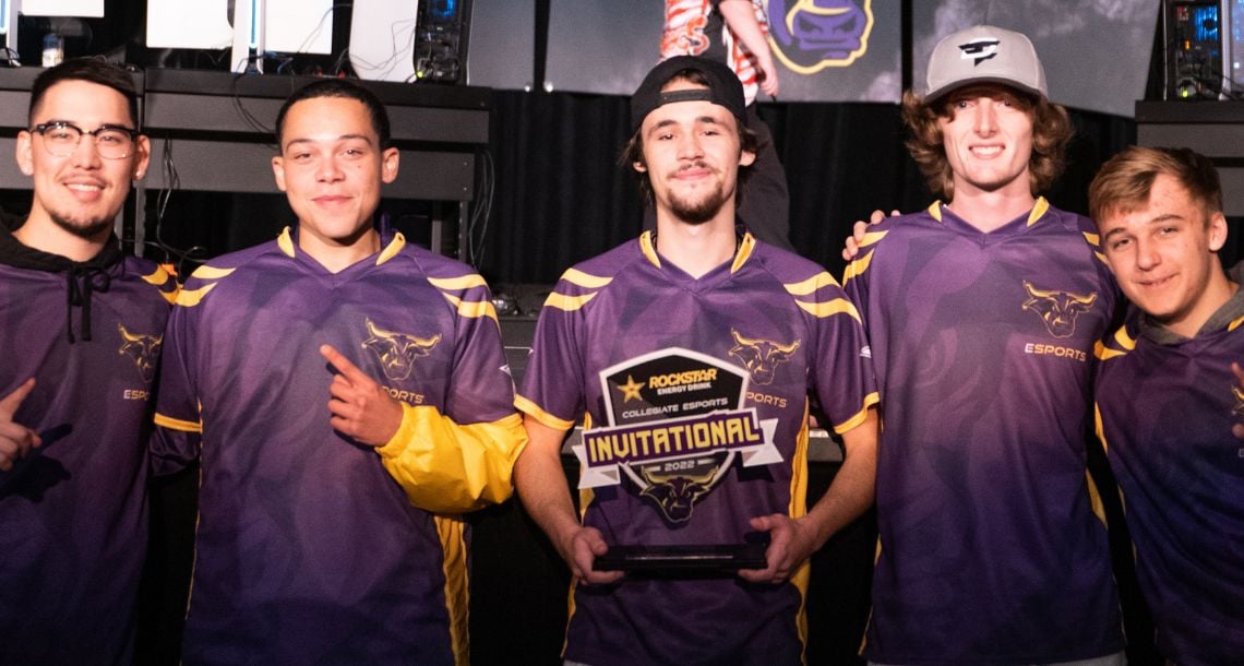 Five players posing with Rockstar Collegete Esports Invitational trophy