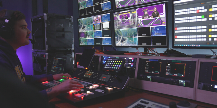 Photo of student working with broadcast equipment, including monitors, keyboards, and more.