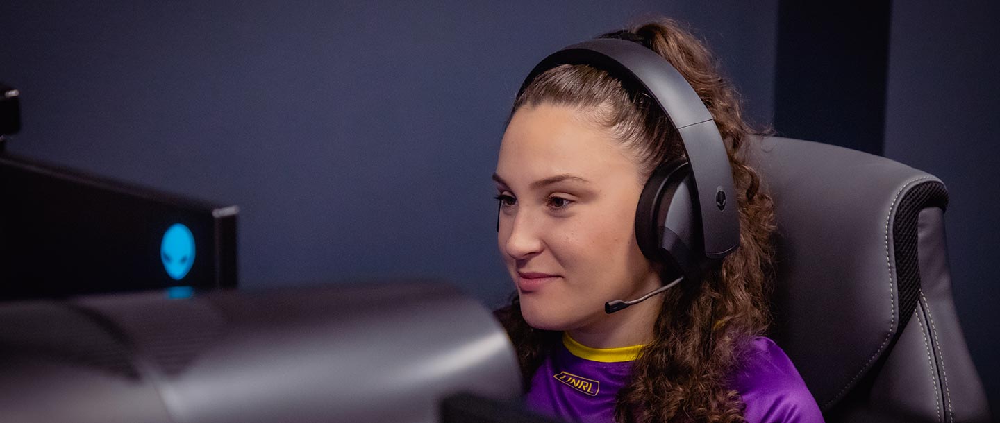 Girl wearing headphones and gaming on a PC in the Esports Training Facility