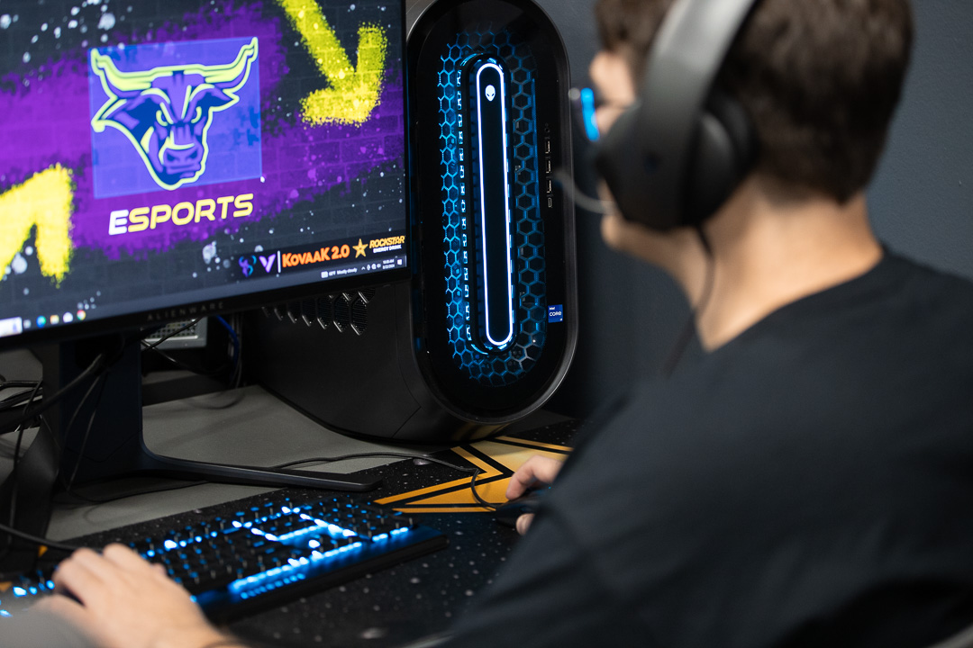 Student wearing headphones and gaming on a PC computer